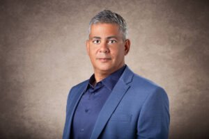 Homem de cabeo grisalho, paletó e camisa azul