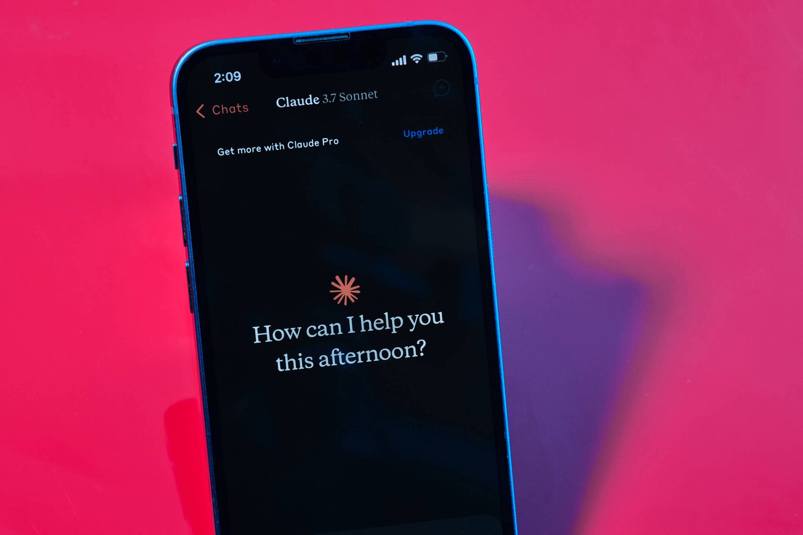 Um smartphone está posicionado em um fundo rosa vibrante. Na tela do celular, há uma interface de assistente virtual com a mensagem:
