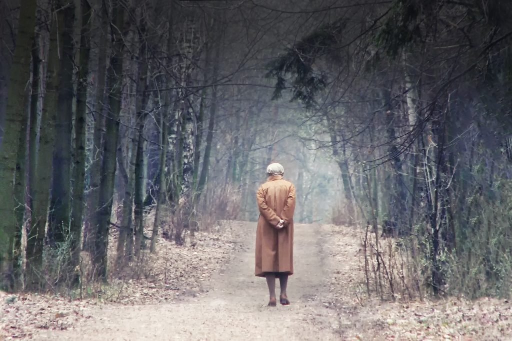 Pessoa de costas, com as mãos nas costas e com a cabeça baixa