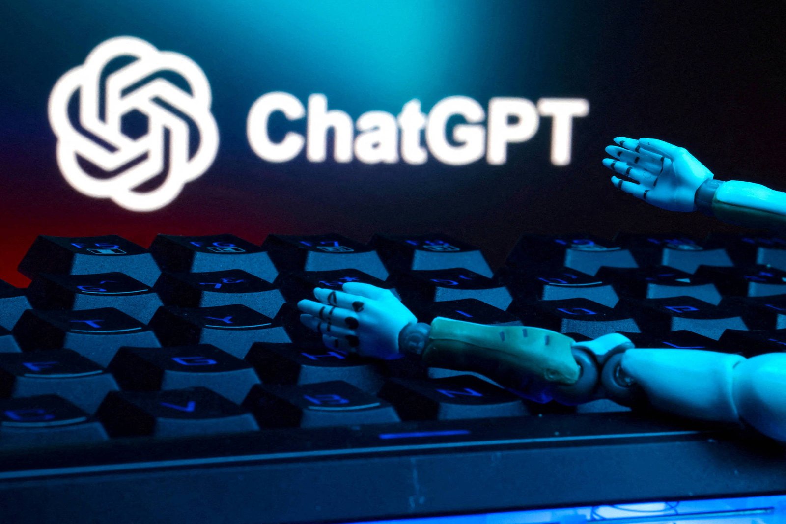 A imagem mostra um teclado com teclas pretas e um braço robótico parcialmente visível, estendido sobre as teclas. Ao fundo, está o logotipo do ChatGPT, que consiste em um símbolo estilizado e o texto