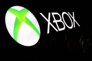 A imagem mostra o logotipo da marca Xbox, que consiste em um círculo branco com um símbolo verde em forma de