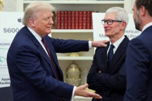 A imagem mostra duas pessoas em um ambiente formal, possivelmente no Salão Oval da Casa Branca. À esquerda, um homem com cabelo claro e terno escuro está sorrindo e gesticulando, enquanto à direita, um homem com cabelo grisalho e óculos está sorrindo e olhando para o outro. Ao fundo, há um cartaz com informações sobre investimentos da Apple, incluindo um valor de $600 milhões e referências a empregos nos Estados Unidos.