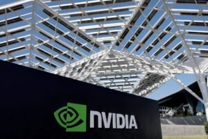 A imagem mostra o logotipo da NVIDIA em um painel preto, com uma estrutura arquitetônica moderna ao fundo, composta por uma cobertura de painéis solares. O logotipo é verde e branco, com um design que inclui um símbolo gráfico e o nome