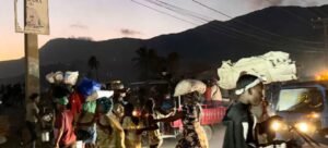 No Haiti, pessoas carregando seus pertences fogem quase na escuridão