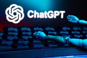 Braços de robô azul posicionados sobre teclado de computador com o logo do ChatGPT iluminado ao fundo em azul.