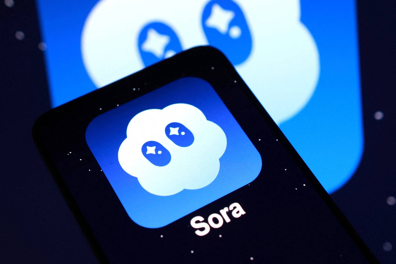 Ícone do aplicativo Sora exibido em tela de smartphone com fundo azul e nuvem branca estilizada com olhos em forma de estrelas.