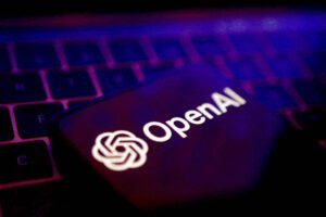 Tela de dispositivo exibe o logotipo branco da OpenAI com símbolo ao lado, sobre teclado escuro com iluminação roxa e azul.