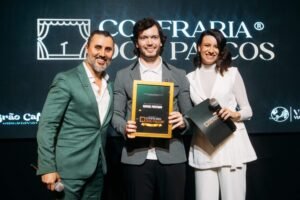 Fernando Freitas e Bruna Grah entregam reconhecimento a um participante da Confraria dos Palcos durante a imersão, representando o método de formação de novos comunicadores.