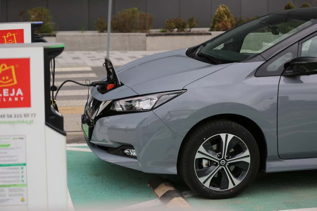 Parte dianteira de um veículo com a tampa de carregamento aberta e um carregador inserido nela