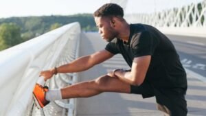 Homem alongando perna em ponte enquanto usa fone da JBL