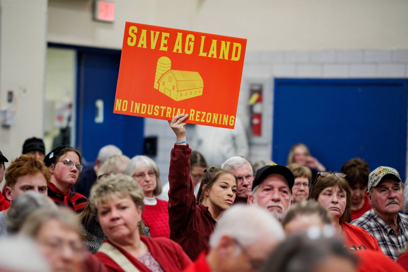 Mulher jovem levanta cartaz vermelho com texto amarelo