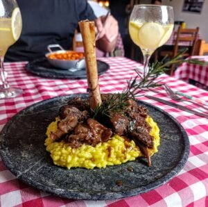 Stinco de cordeiro no Mizzica - maturado e cozido lentamente em baixa temperatura, alcançando uma textura extremamente macia e suculenta.