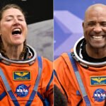 Dois astronautas vestindo trajes espaciais laranja da NASA aparecem em imagens lado a lado. À esquerda, mulher com tranças sorri com boca aberta contra fundo escuro. À direita, homem careca sorri amplamente diante de fundo azul com padrão geométrico.