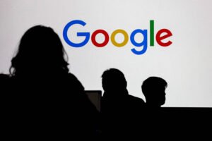 Três silhuetas de pessoas em primeiro plano observam uma tela branca com o logo colorido do Google ao centro.