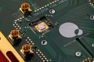 Placa de circuito verde com chip central pequeno cercado por conexões douradas e componentes eletrônicos. Texto
