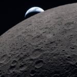 Superfície da Lua com várias crateras visíveis em primeiro plano e a Terra parcialmente iluminada surgindo no horizonte escuro do espaço.