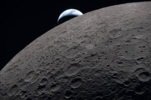 Superfície da Lua com várias crateras visíveis em primeiro plano e a Terra parcialmente iluminada surgindo no horizonte escuro do espaço.