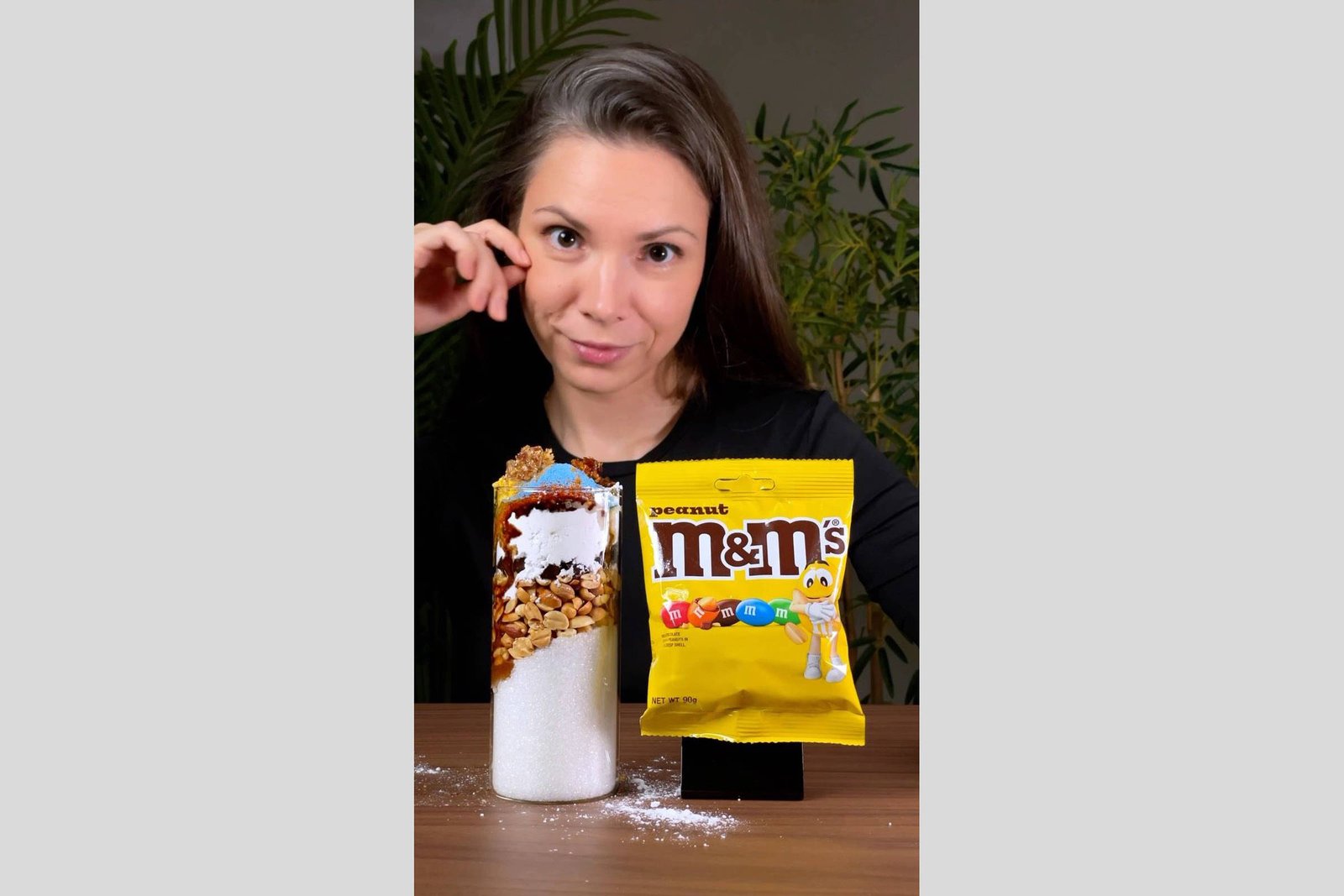 Mulher de cabelos castanhos e lisos segura embalagem amarela de M&M