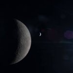 Lua em fase crescente aparece em primeiro plano com superfície detalhada e crateras visíveis. Ao fundo, um planeta menor iluminado parcialmente, ambos em espaço escuro com reflexos de luz.